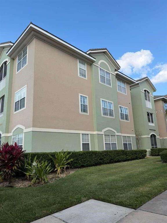 A multi-story apartment building with beige and green stucco siding and a manicured lawn — 4865 CYPRESS WOODS DRIVE UNIT 2302, ORLANDO, FL