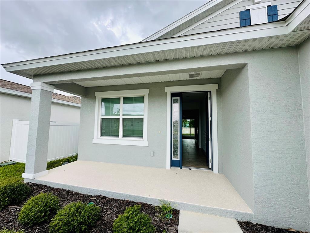 A light gray house exterior features a covered front porch, a window, and an open door — 5806 SW 78TH AVENUE ROAD, OCALA, FL