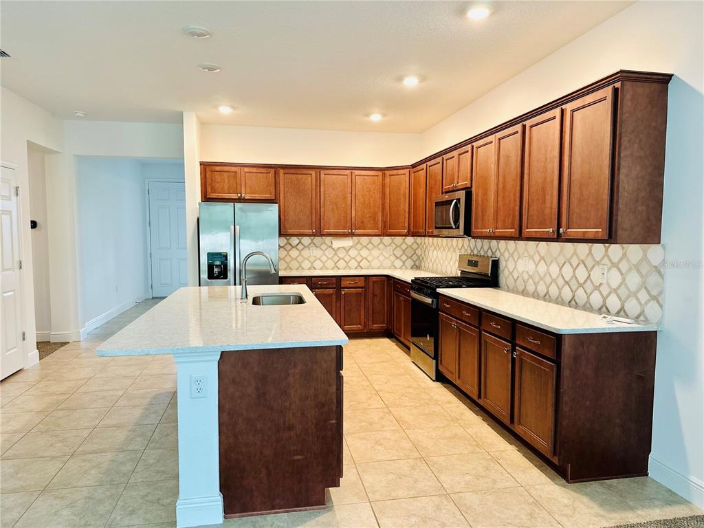 A kitchen features dark wood cabinets, light countertops, a center island, and tiled flooring — 5806 SW 78TH AVENUE ROAD, OCALA, FL