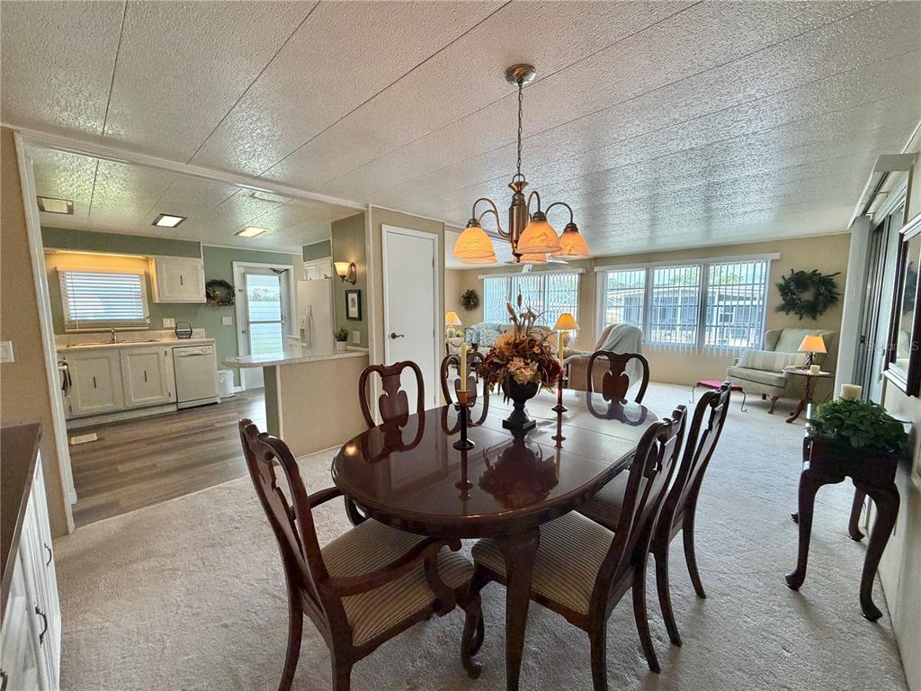 A dining area with a wooden table and chairs sits adjacent to a kitchen — 117 JACARANDA DRIVE, LEESBURG, FL