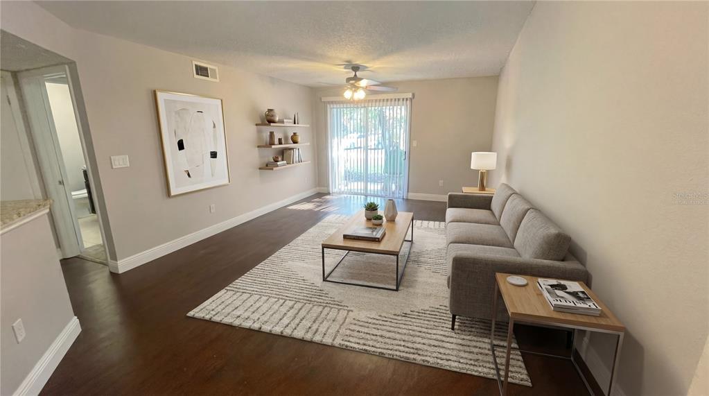 A living room features a gray sofa, a wooden coffee table, and wall-mounted shelves — 1948 LAKE ATRIUMS CIRCLE UNIT 113, ORLANDO, FL