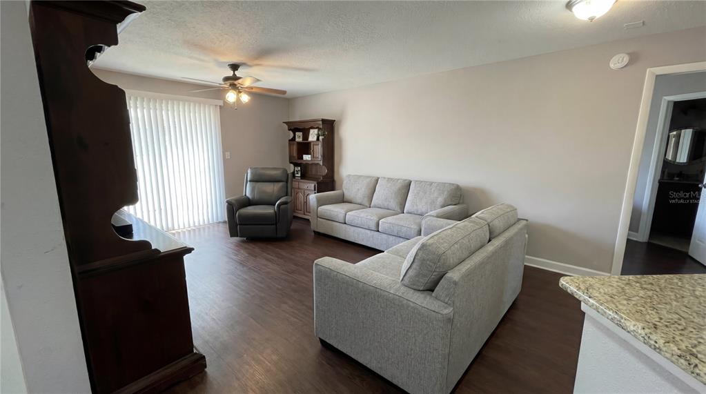 A living room features light gray sofas, a recliner, wood-look flooring, and a wooden hutch — 1948 LAKE ATRIUMS CIRCLE UNIT 113, ORLANDO, FL