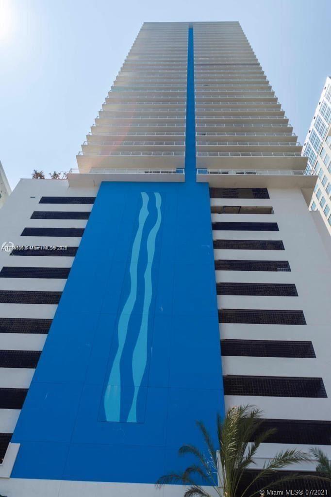 A low-angle exterior view of a tall residential skyscraper featuring a prominent blue vertical accent — 1200 Brickell Bay Dr # 3924, Miami FL 33131, MIAMI, FL
