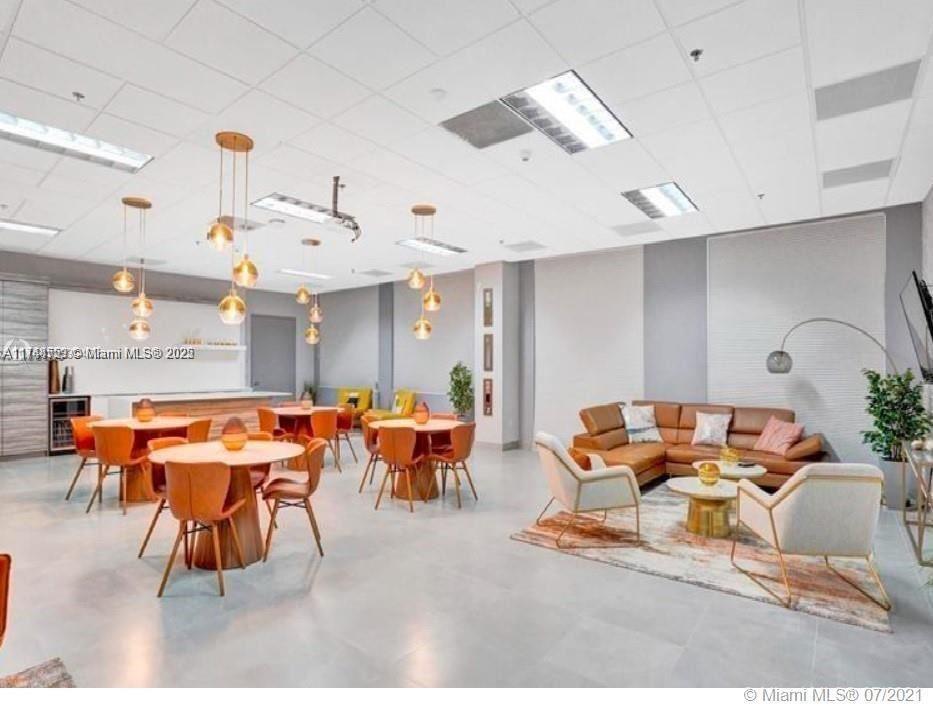 A modern office lounge features multiple dining tables, a leather sectional, and pendant lighting — 1200 Brickell Bay Dr # 3924, Miami FL 33131, MIAMI, FL