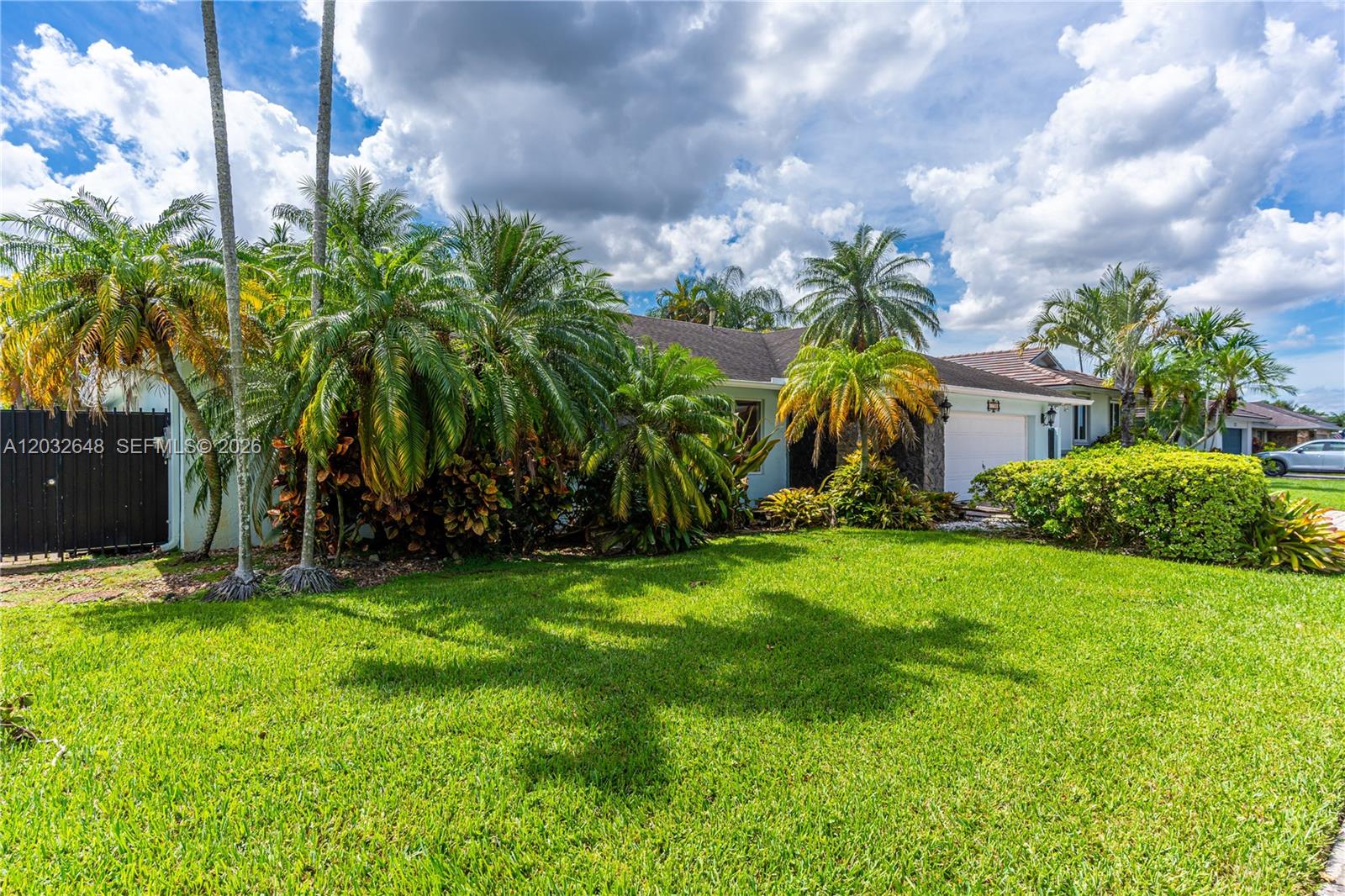 A single-story house with a white garage and palm trees sits behind a green lawn — 11728 SW 97th St # 0, Miami FL 33186, MIAMI, FL