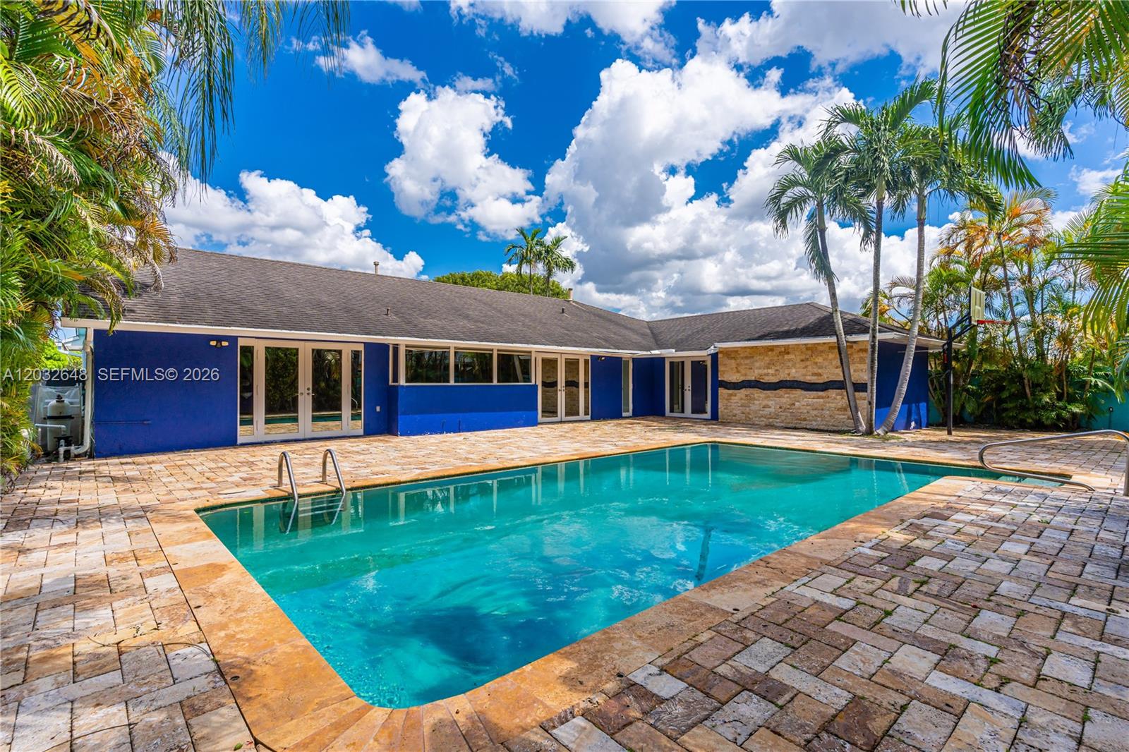 A blue house with a stone accent wall overlooks a rectangular swimming pool and patio — 11728 SW 97th St # 0, Miami FL 33186, MIAMI, FL