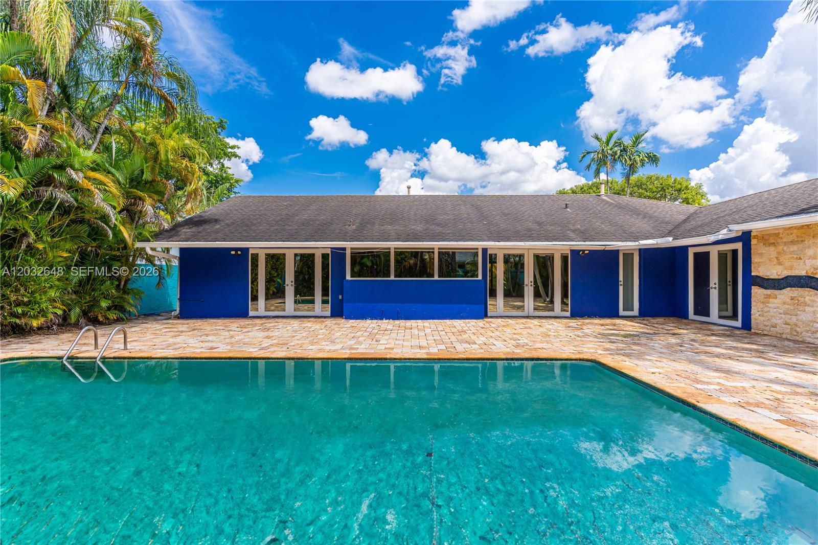 A blue house exterior features a swimming pool and a paved patio under a sky — 11728 SW 97th St # 0, Miami FL 33186, MIAMI, FL