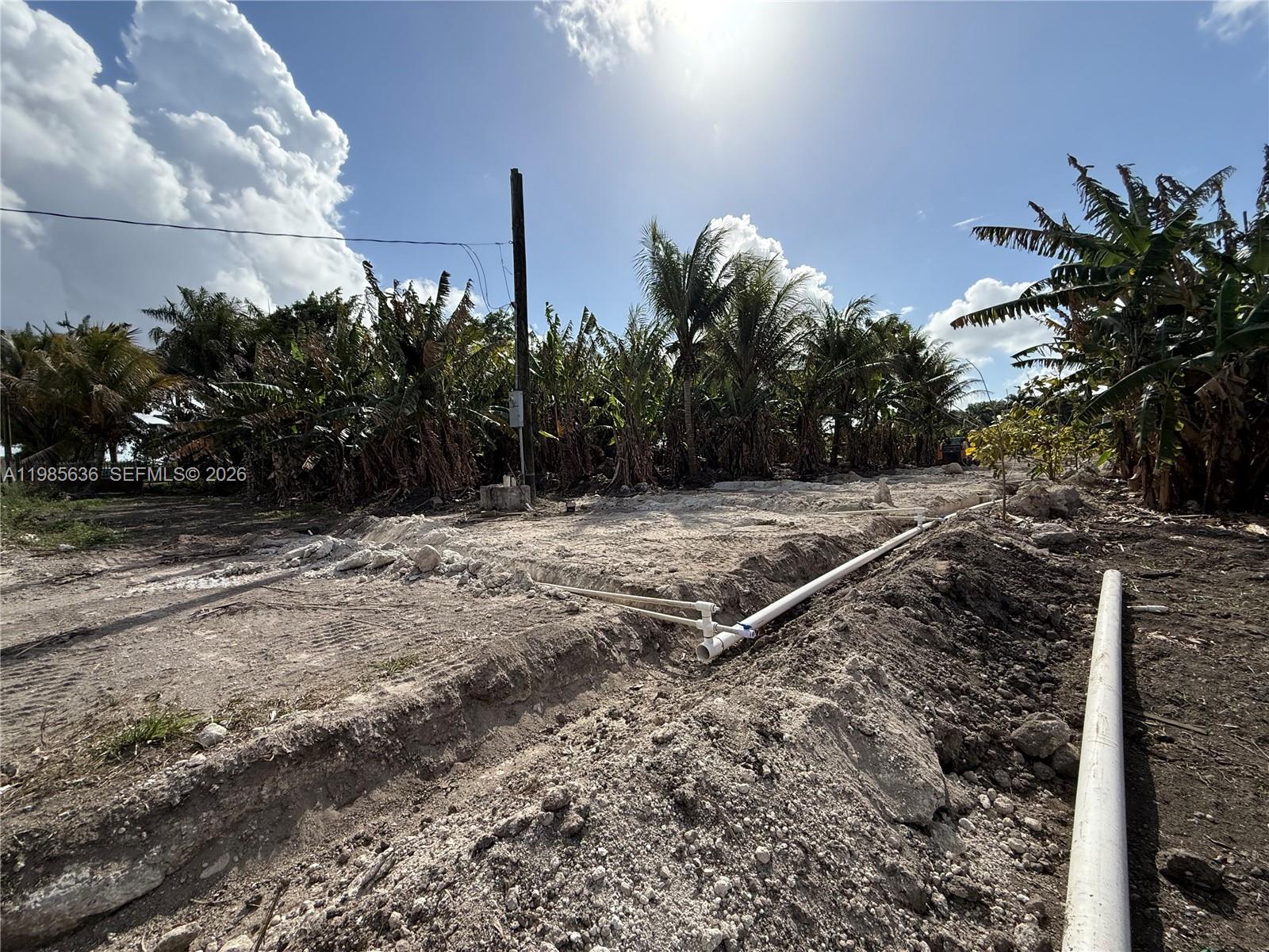 A dirt lot features exposed white PVC piping laid out in trenches for construction — 16455 SW 207, Miami FL 33187, MIAMI, FL