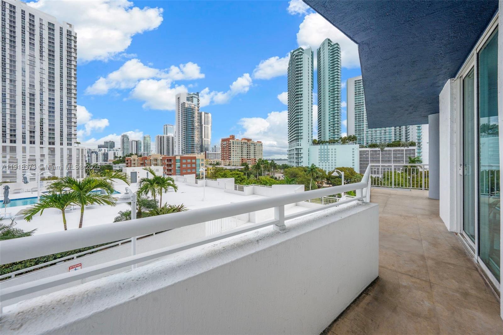 A balcony with a white railing overlooks a swimming pool and a city skyline — 275 NE 18th St # 708, Miami FL 33132, MIAMI, FL