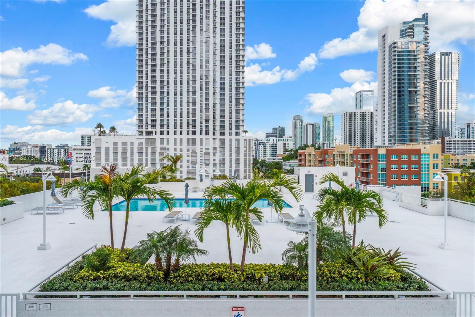 A rooftop pool deck features palm trees, lounge chairs, and views of surrounding city skyscrapers — 275 NE 18th St # 708, Miami FL 33132, MIAMI, FL