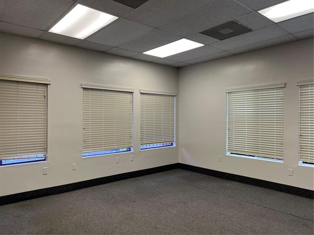 An empty office room features gray carpeting, white walls, and multiple windows with closed blinds — 1173 SPRING CENTRE SOUTH BOULEVARD UNIT A, ALTAMONTE SPRINGS, FL
