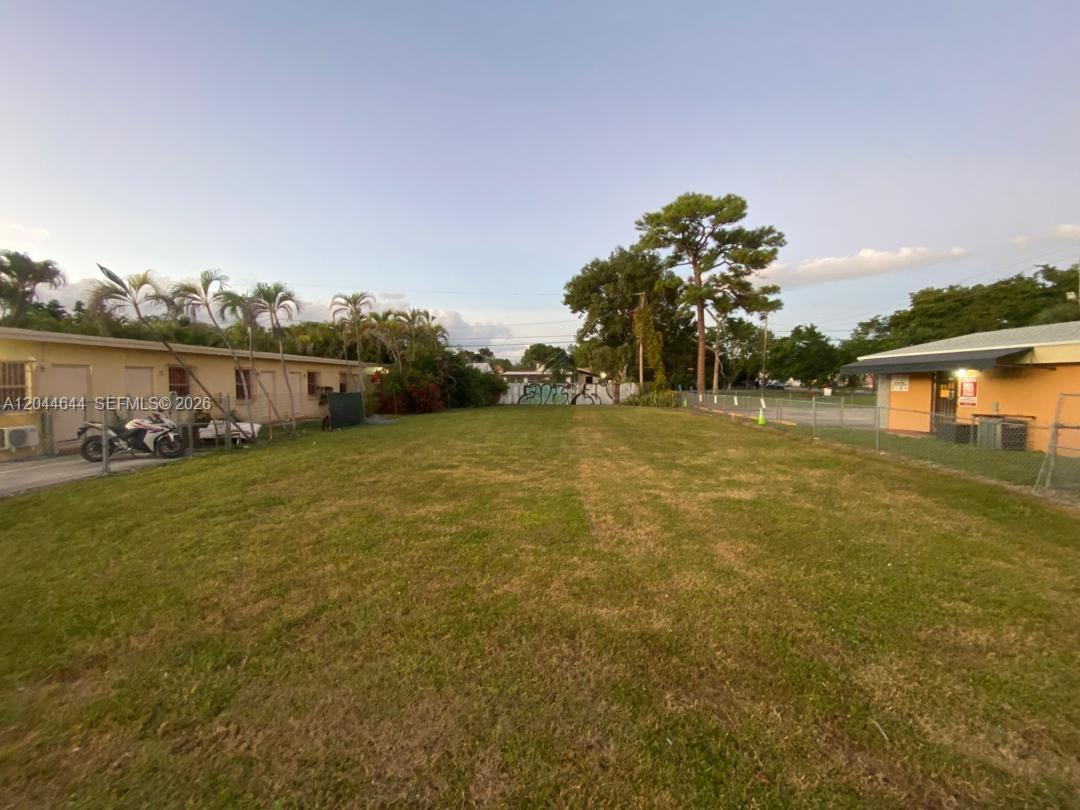 A grassy vacant lot sits between a low-rise building and a fenced parking area — 3021 W Flagler St, Miami FL 33135, MIAMI, FL