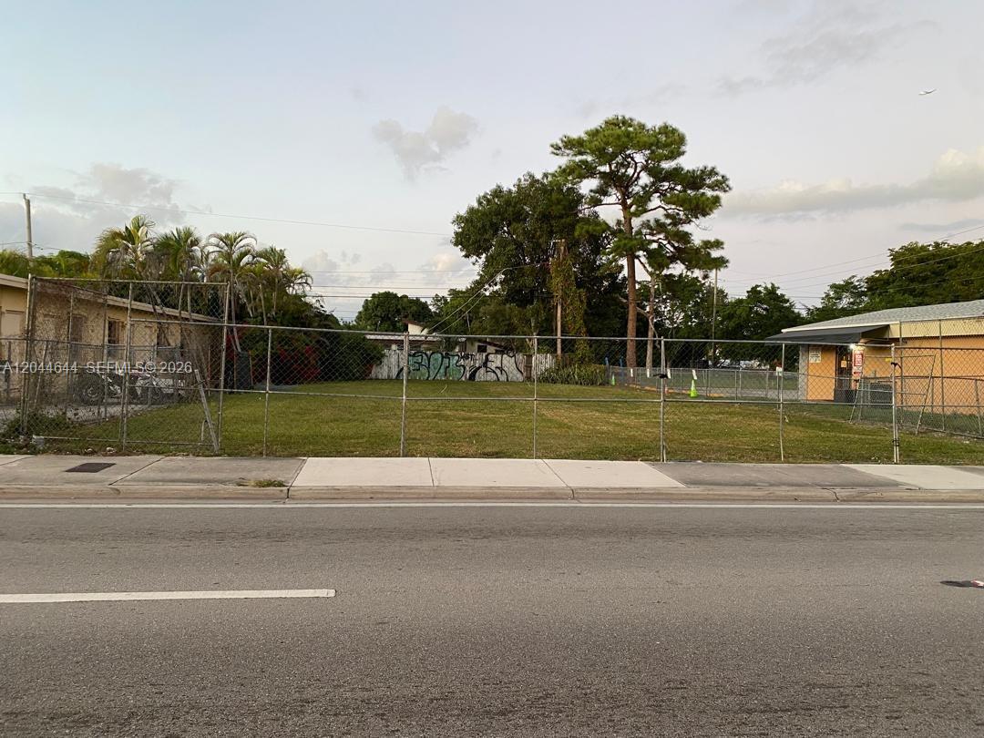 A fenced, vacant grassy lot sits between two buildings along a paved road — 3021 W Flagler St, Miami FL 33135, MIAMI, FL