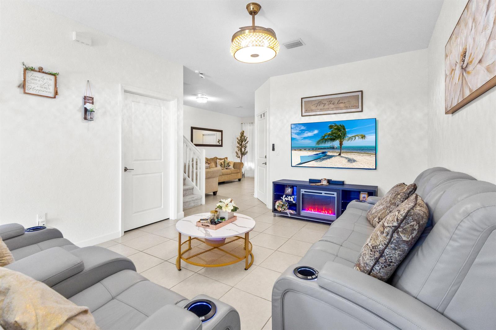 A living room features light tile flooring, gray leather sofas, a fireplace console, and a chandelier — 2688 NW 55th Terrace, Lauderhill FL 33313, LAUDERHILL, FL