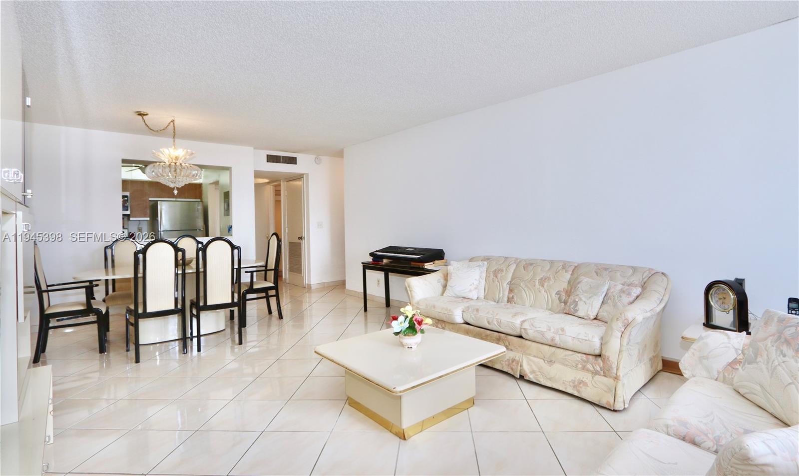 A living room and dining area with tile floors, a floral sofa, and a chandelier — 2401 S Ocean Dr # 806, Hollywood FL 33019, HOLLYWOOD, FL