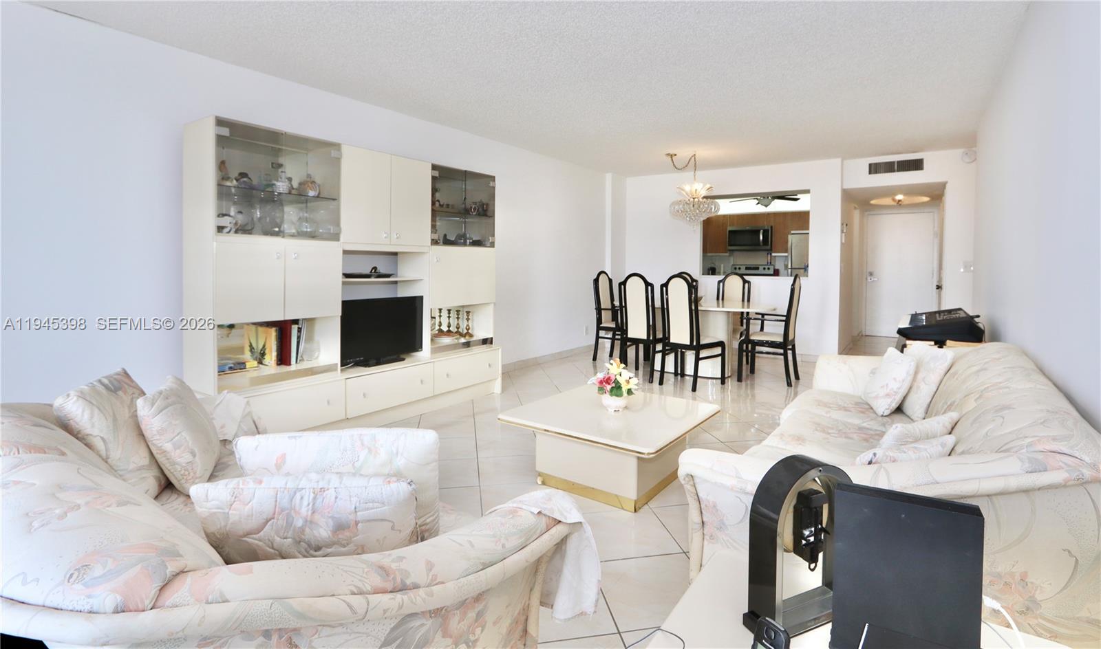 A living and dining area features tile floors, floral-patterned sofas, and a large wall unit — 2401 S Ocean Dr # 806, Hollywood FL 33019, HOLLYWOOD, FL