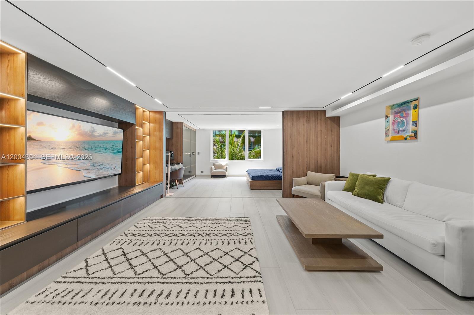 A modern open-plan living area features a large television, wooden cabinetry, and a white sofa — 2301 Collins Ave # 432, Miami Beach FL 33139, MIAMI BEACH, FL