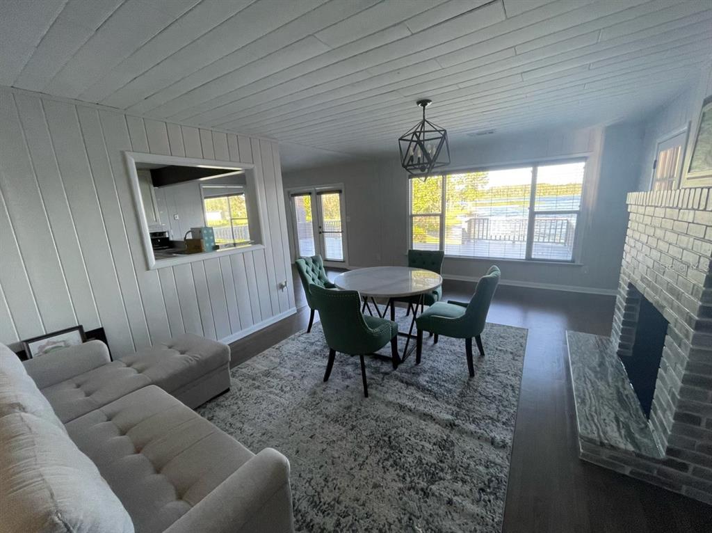 A living and dining area features white wood-paneled walls, a brick fireplace, and lake views — 940 N KEPLER ROAD, DELAND, FL