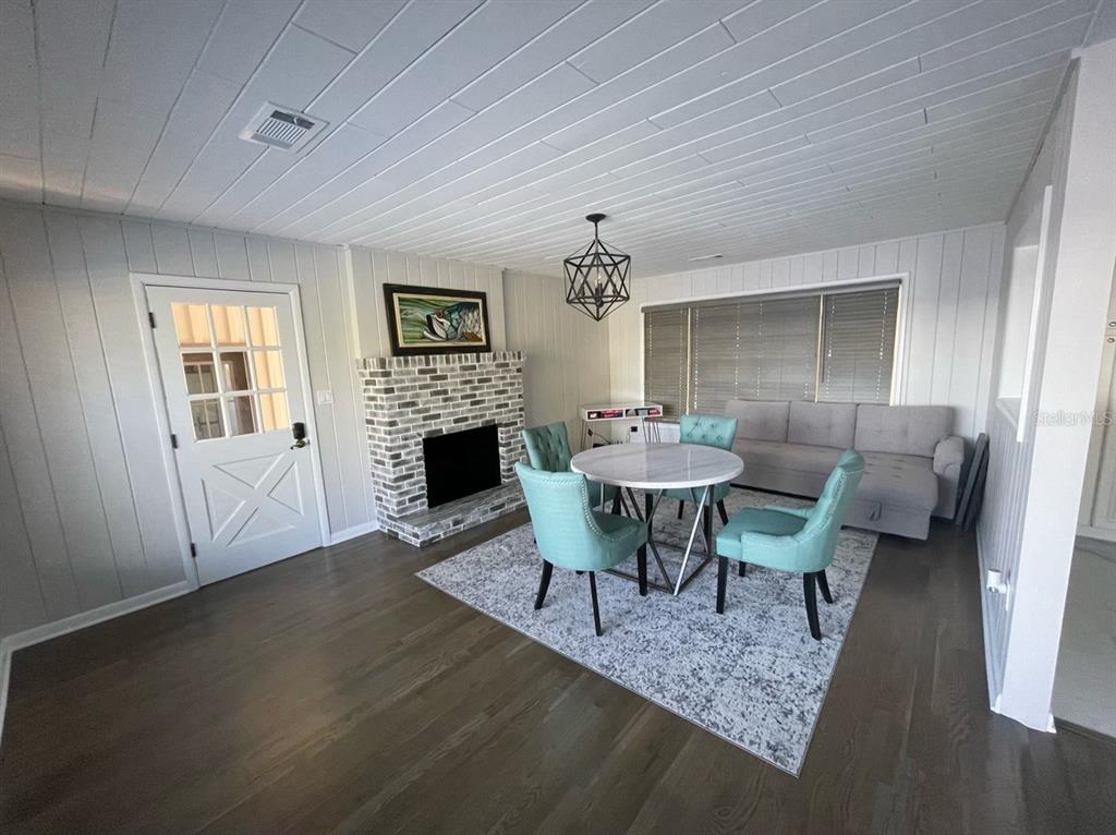 A dining area features a brick fireplace, light wood flooring, and a white plank ceiling — 940 N KEPLER ROAD, DELAND, FL