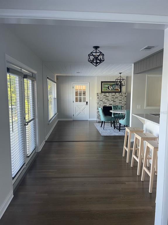 A view of a dining area with a brick fireplace, hardwood floors, and bar seating — 940 N KEPLER ROAD, DELAND, FL
