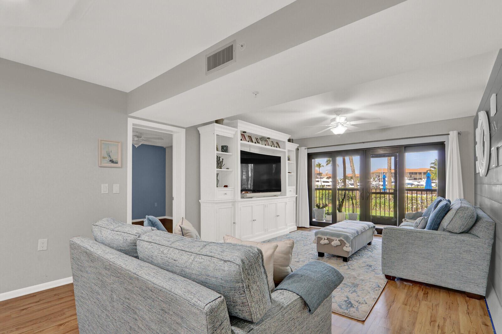 A living room features light blue sofas, a white entertainment center, and sliding glass doors — 701 SEAFARER Circle # 105, Jupiter FL 33477, JUPITER, FL