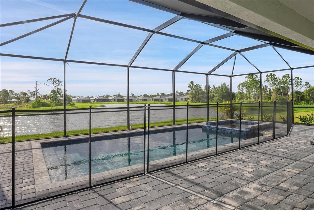 A screened-in patio features a rectangular swimming pool, a hot tub, and paver flooring — 19100 MOSCATO COURT, VENICE, FL