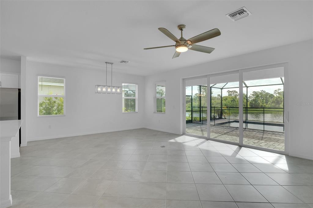 A bright, open-concept dining area features light tile floors, a ceiling fan, and sliding doors — 19100 MOSCATO COURT, VENICE, FL