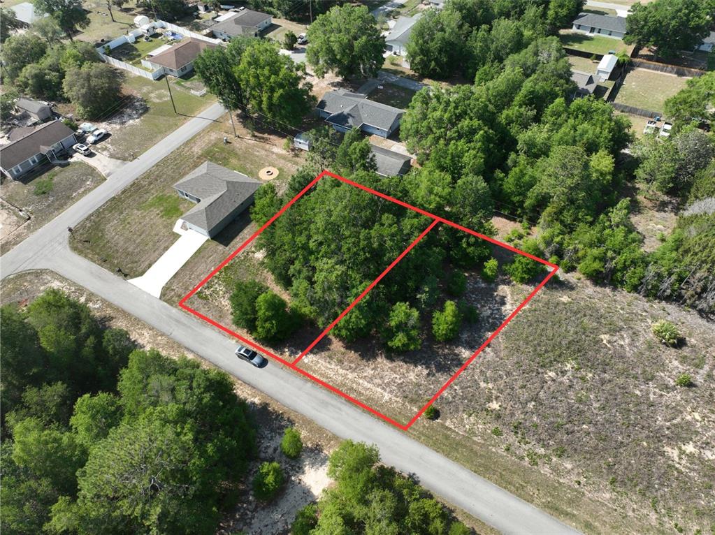 An aerial view shows two adjacent, wooded, undeveloped residential lots outlined in red — SW 83RD ST, DUNNELLON, FL