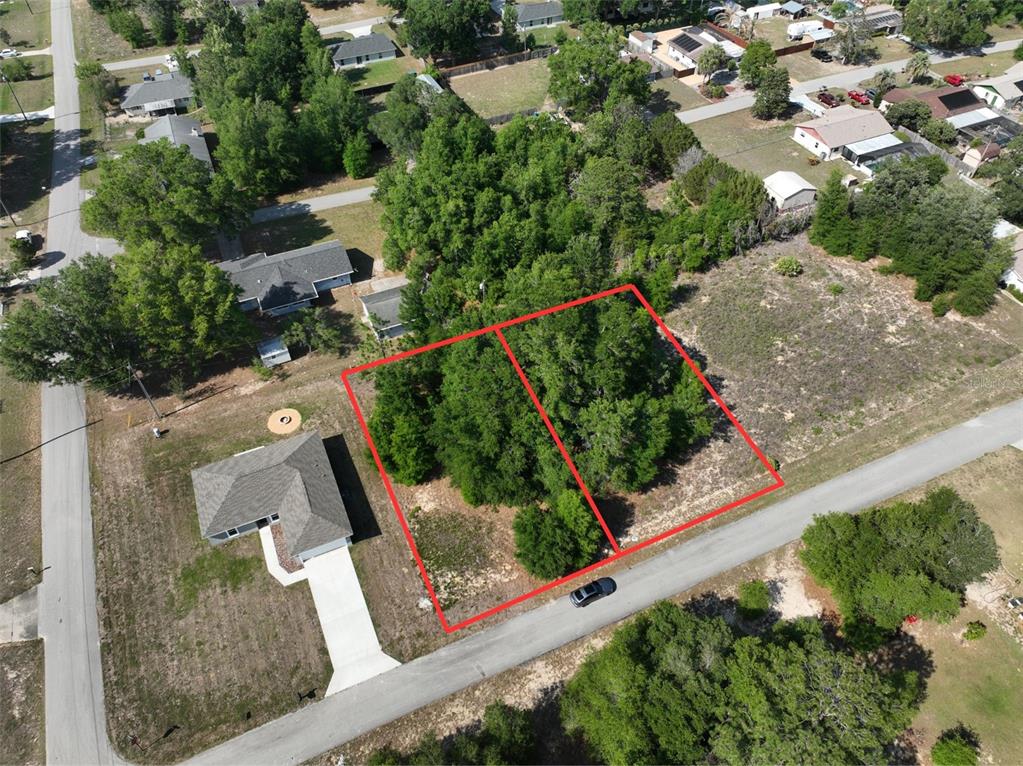 An aerial view shows two adjacent, wooded, undeveloped lots outlined in red along a road — SW 83RD ST, DUNNELLON, FL
