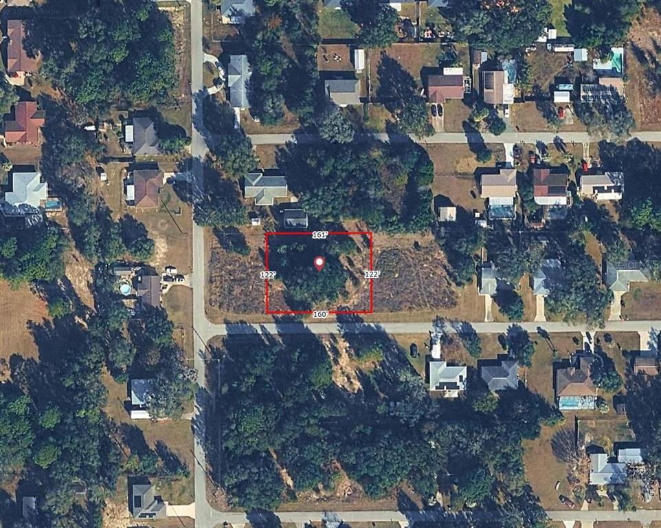 An aerial view shows a rectangular vacant lot outlined in red within a residential neighborhood — SW 83RD ST, DUNNELLON, FL