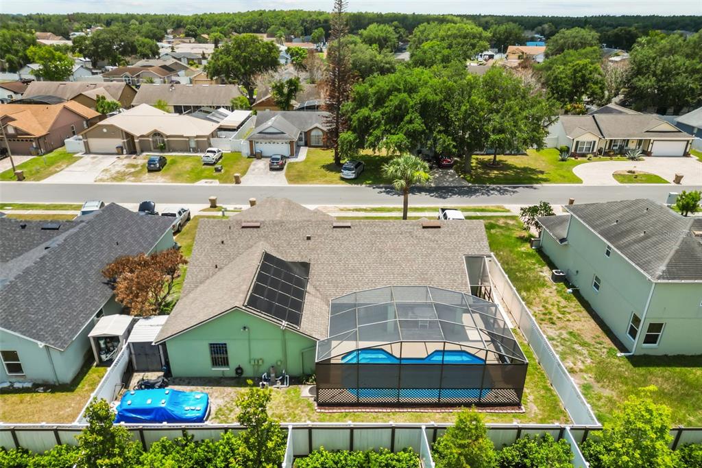 An aerial view shows a house with a pool enclosure and solar panels on the roof — 213 COMPETITION DRIVE, KISSIMMEE, FL