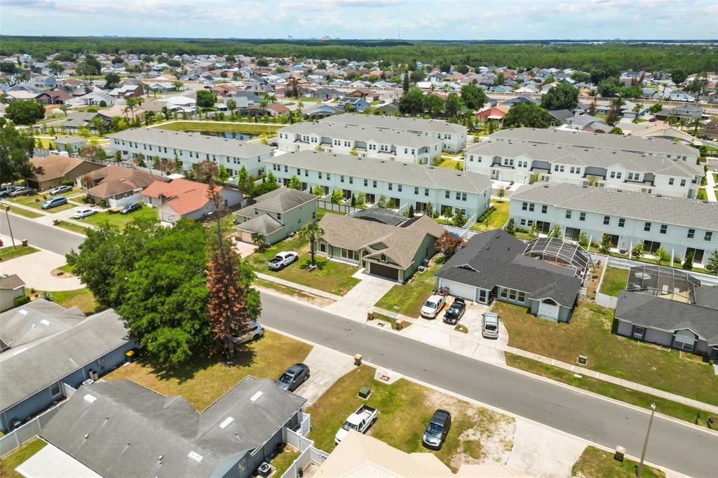 An aerial view shows suburban houses, townhomes, and streets under a blue sky — 213 COMPETITION DRIVE, KISSIMMEE, FL