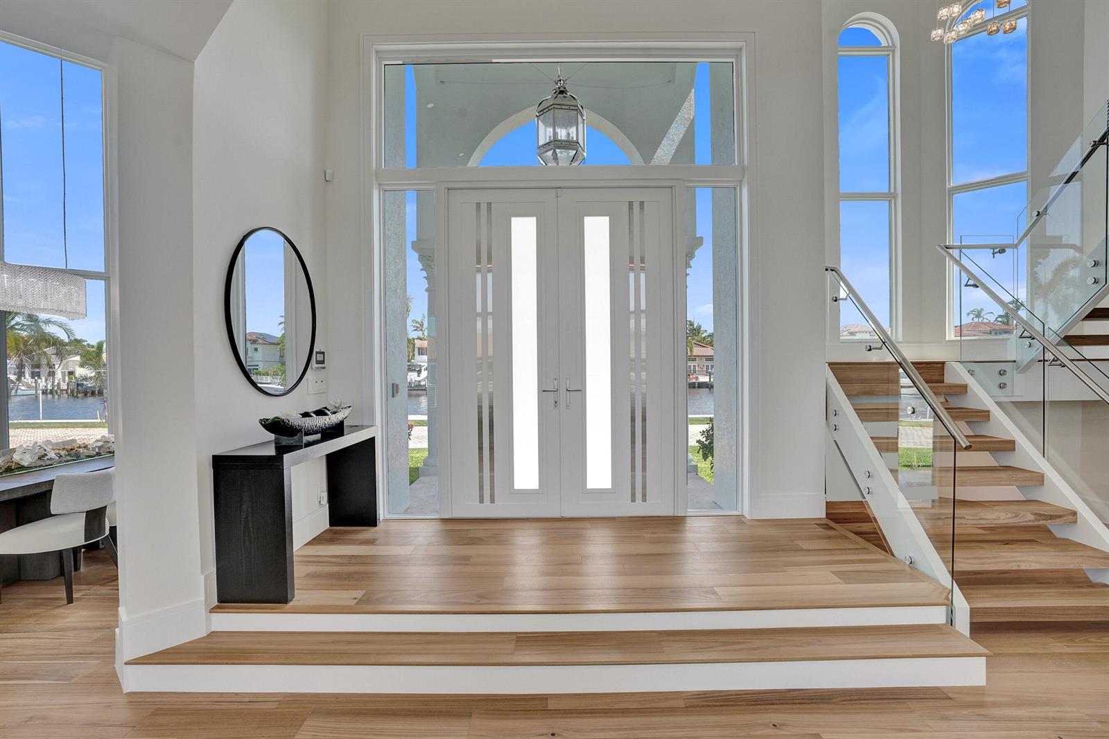 A bright entryway features a double front door, light wood flooring, and a glass staircase — 890 Lilac Drive, Boca Raton FL 33487, BOCA RATON, FL