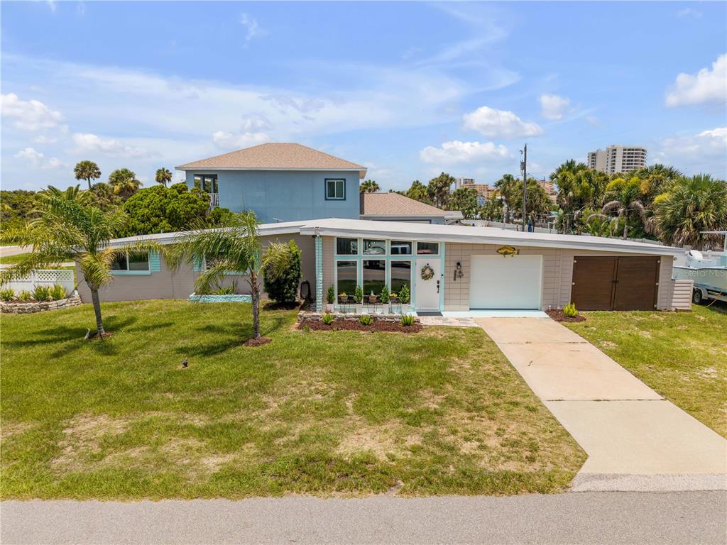A single-story house with a flat roof, a white garage door, and a concrete driveway — 3929 S PENINSULA DRIVE, PORT ORANGE, FL