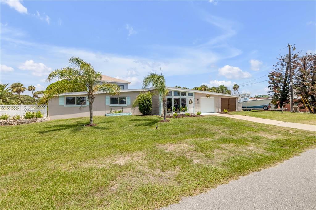 A single-story house with a light-colored exterior, palm trees, and a boat parked in the yard — 3929 S PENINSULA DRIVE, PORT ORANGE, FL