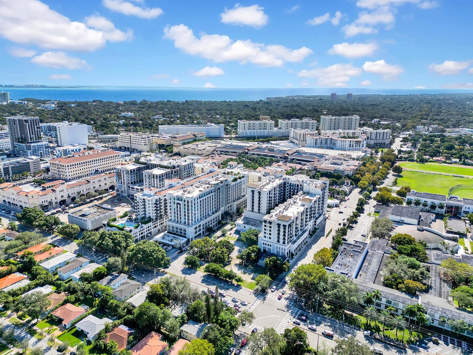 An aerial view shows a dense urban neighborhood with modern apartment buildings and nearby greenery — 4070 Laguna St, Coral Gables FL 33146, CORAL GABLES, FL