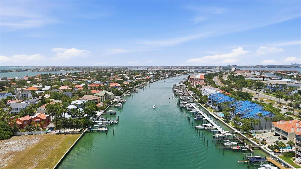 An aerial view of a canal lined with residential homes, boat docks, and blue-roofed townhouses — 910 PINELLAS BAYWAY S UNIT 201, TIERRA VERDE, FL