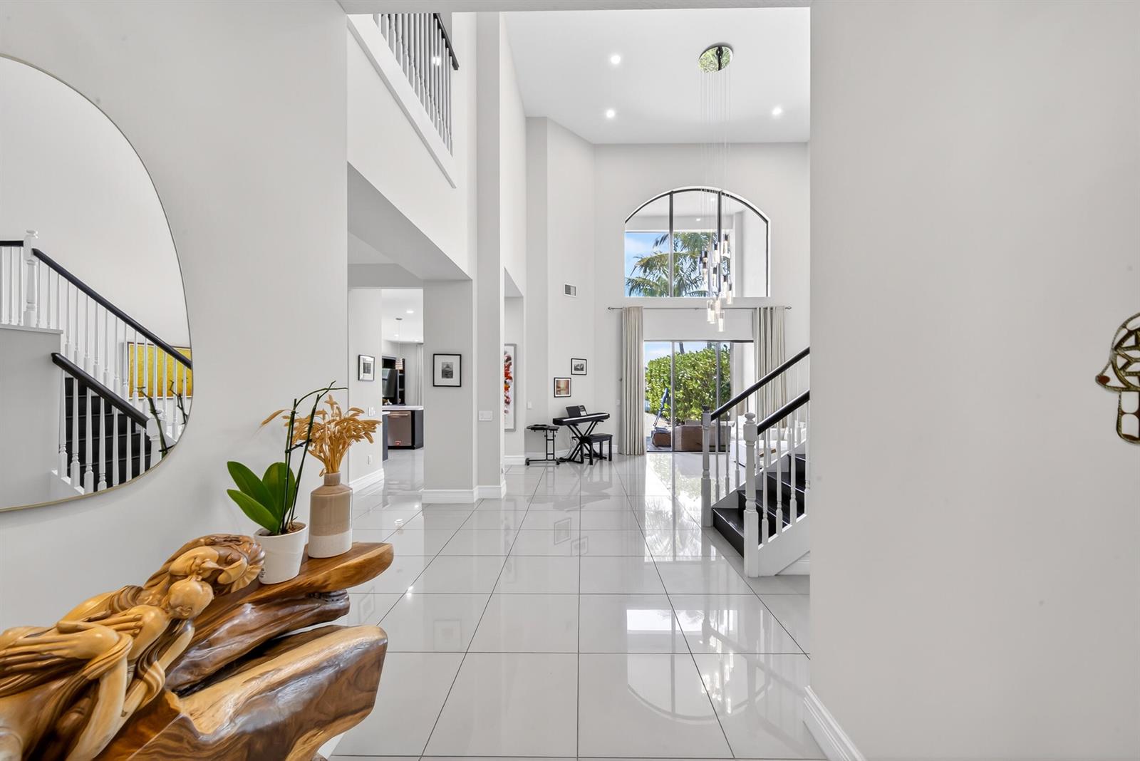 A bright, modern foyer features white tile floors, a grand staircase, and a high ceiling — 16829 Newark Bay Road, Delray Beach FL 33446, DELRAY BEACH, FL