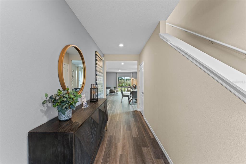 A hallway features wood-look flooring, a dark console table with a mirror, and a staircase — 2121 RED ROCK ROAD, NEW SMYRNA BEACH, FL