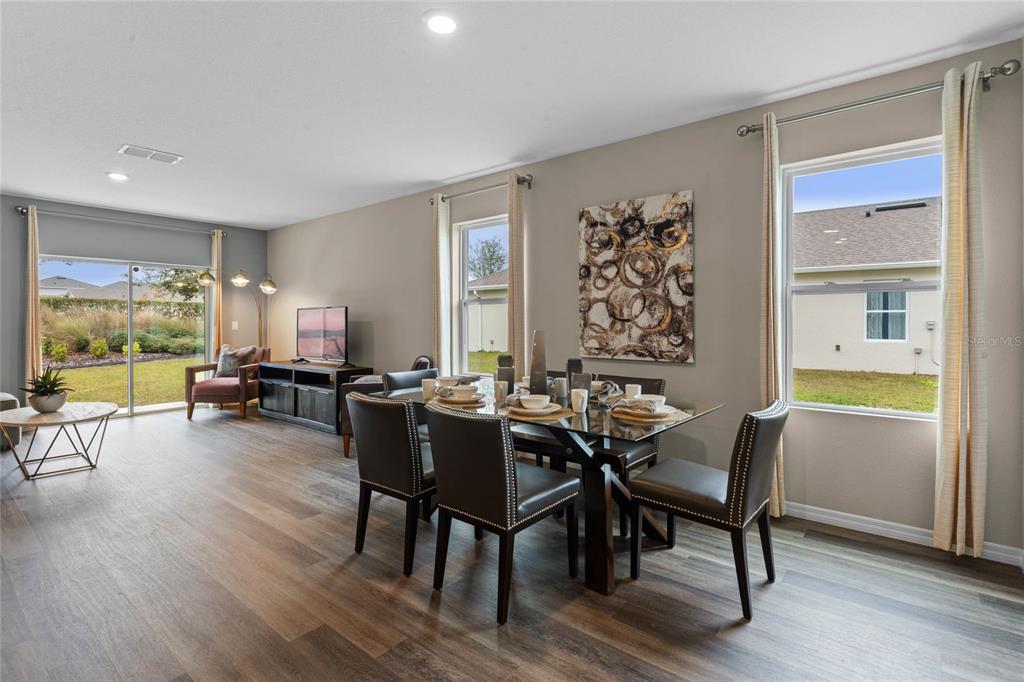 A dining area with a glass table and chairs sits next to a living space — 2121 RED ROCK ROAD, NEW SMYRNA BEACH, FL