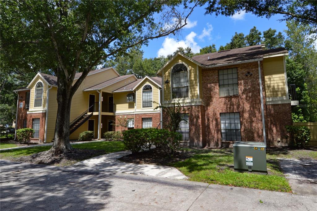 A two-story apartment building with brick and yellow siding features an exterior staircase — 8630 MALLARD RESERVE DRIVE UNIT 103, TAMPA, FL