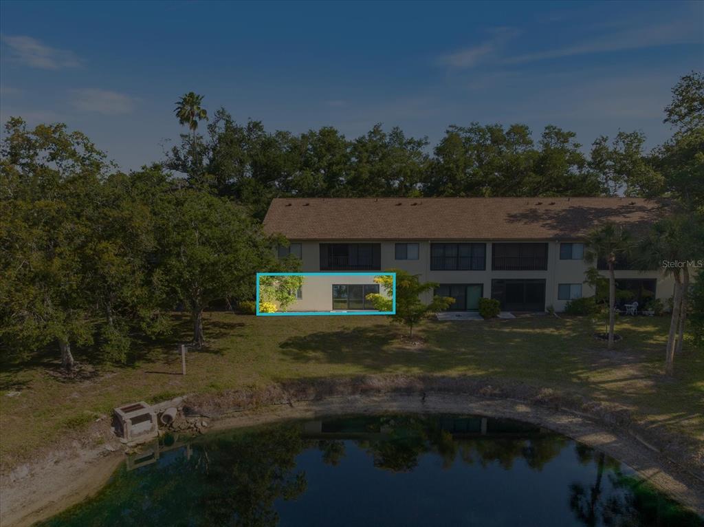 An exterior view of a two-story apartment building with a pond in the foreground — 772 BIRD BAY DRIVE N UNIT 104, VENICE, FL