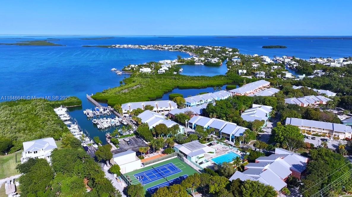 An aerial view shows a coastal residential complex with a marina, tennis court, and pool — 9812 Windward Ave, Key Largo FL 33037, KEY LARGO, FL