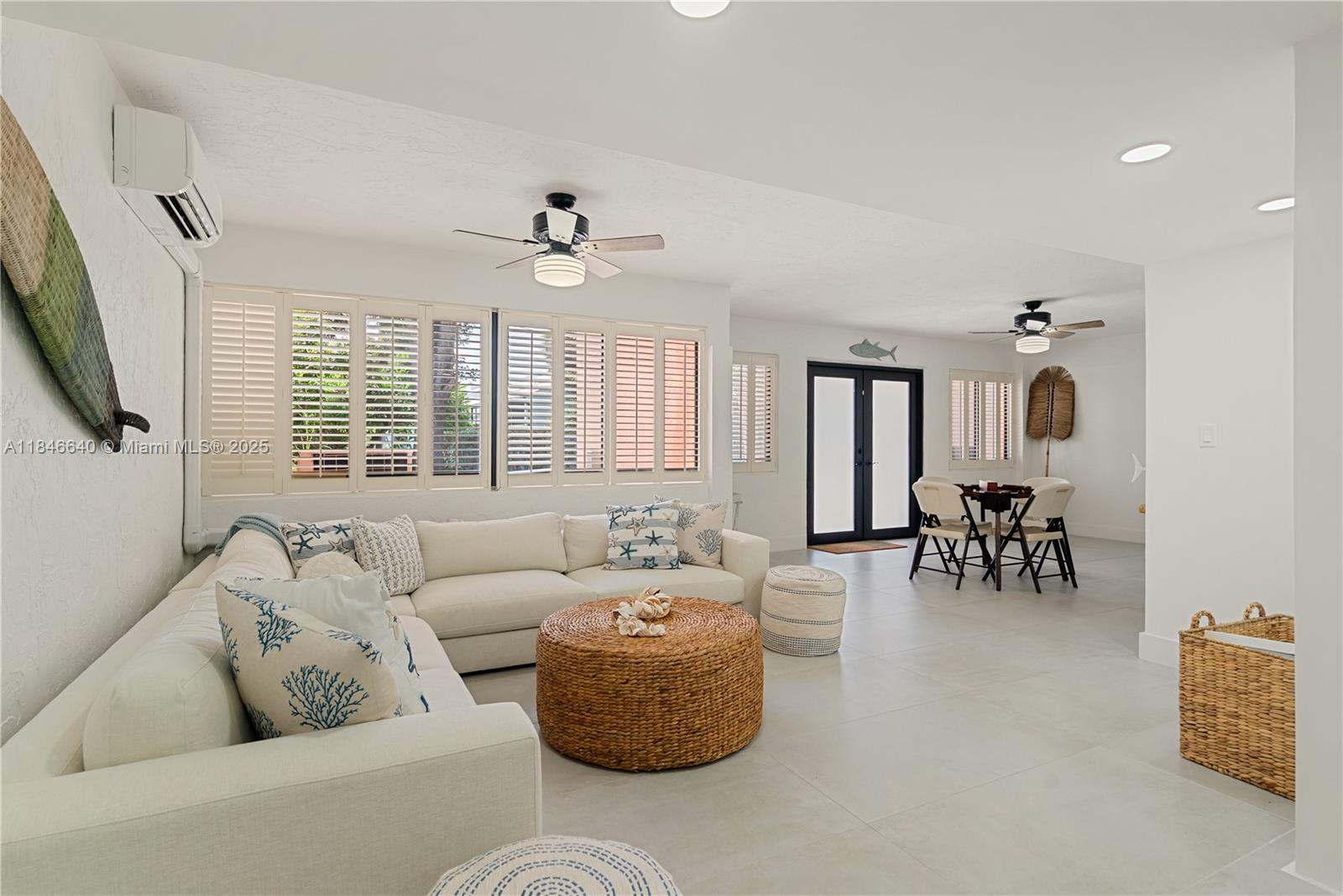 A bright living room features a white sectional sofa, a round wicker coffee table, and tile flooring — 9812 Windward Ave, Key Largo FL 33037, KEY LARGO, FL