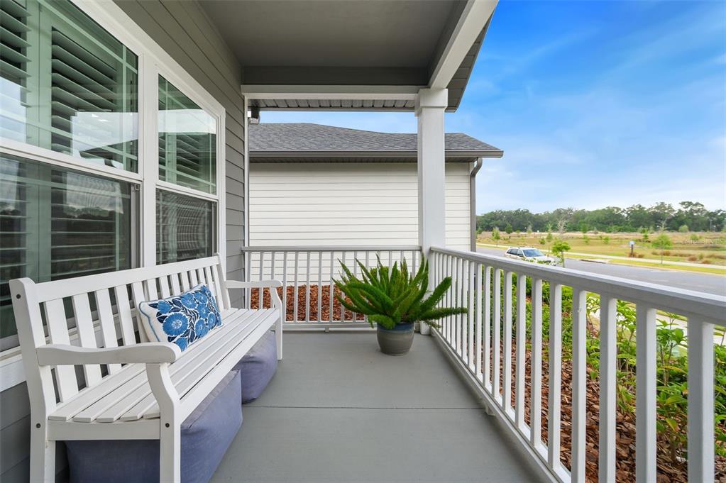 A covered porch features a white wooden bench, a potted plant, and white railings — 9670 SW 68TH LANE, GAINESVILLE, FL
