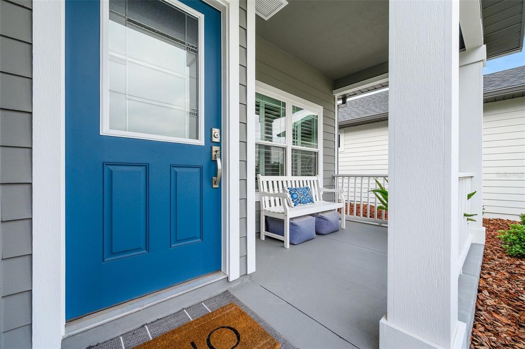 A blue front door opens onto a covered porch featuring a white bench and railing — 9670 SW 68TH LANE, GAINESVILLE, FL