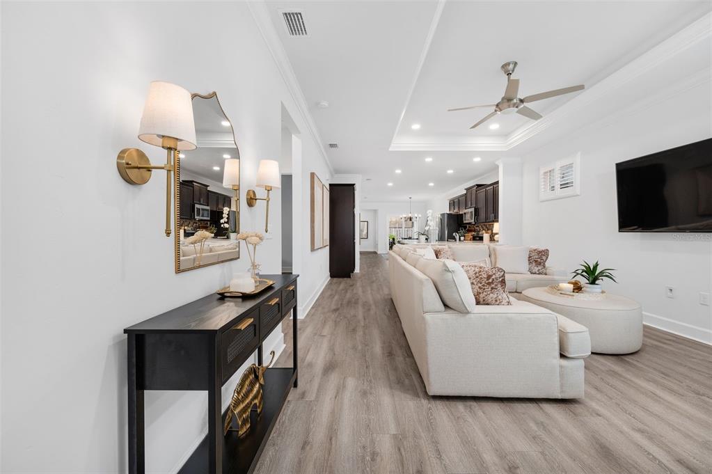 A living room with a beige sectional sofa, a black console table, and wood flooring — 9670 SW 68TH LANE, GAINESVILLE, FL