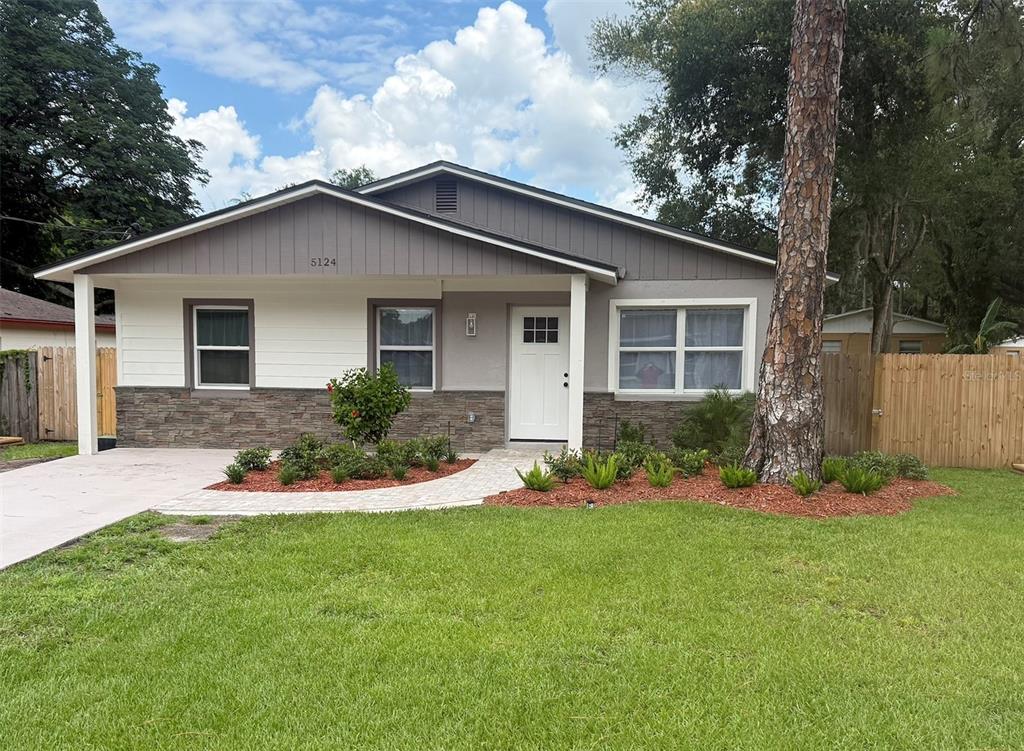 A single-story house with a gray and white exterior, stone accents, and a concrete driveway — 5124 CHILKOOT STREET, TAMPA, FL