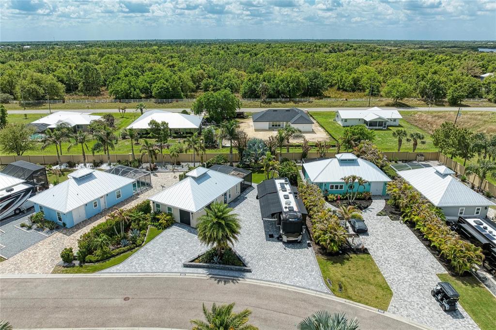 An aerial view shows several houses with metal roofs, paved driveways, and RVs in a neighborhood — 8602 SW SAND CRANE CIRCLE LOT 51, ARCADIA, FL