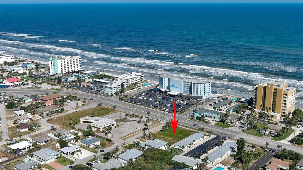 An aerial view shows a vacant lot marked by a red arrow near the beach — 837 7TH STREET, NEW SMYRNA BEACH, FL